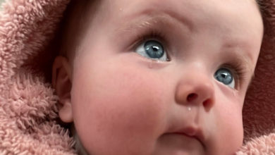 Blue-eyed baby with tears forming looking upward.