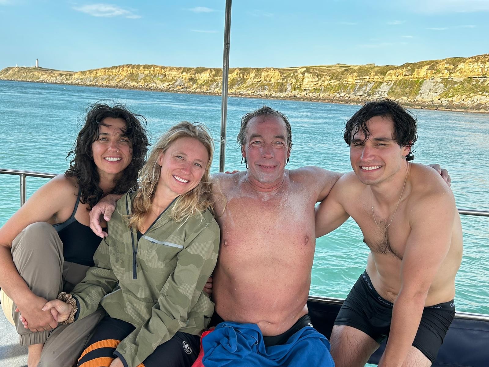 Four individuals in back of a boat looking at camera.