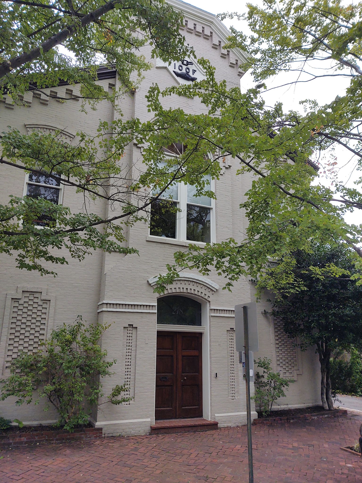 Cream colored townhouse with dark door and four letters high atop on the facade, IOOF.