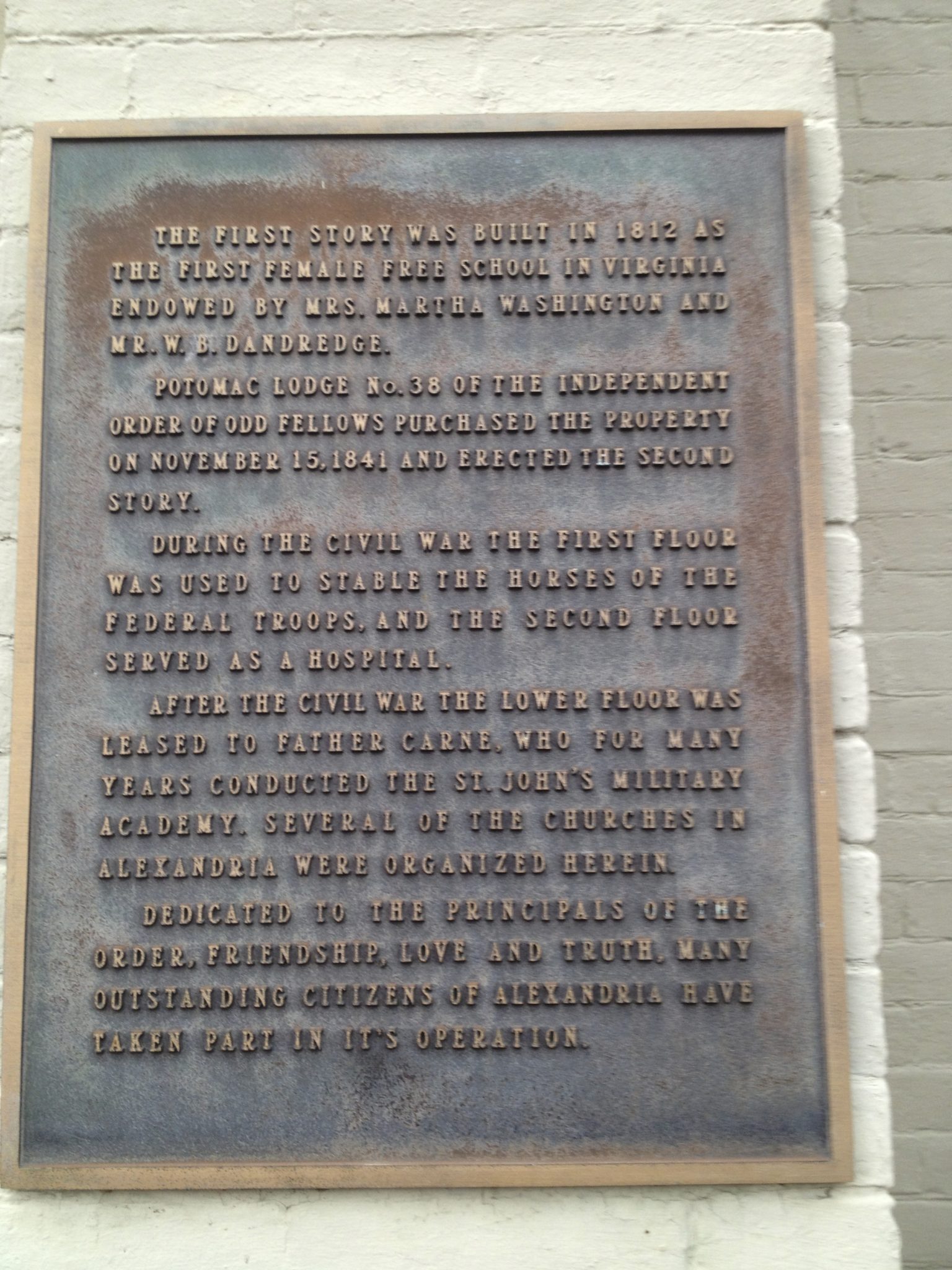 Old brass historic marker with four paragraphs of writing.