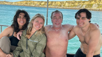 Four individuals in back of a boat looking at camera.