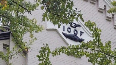 Cream colored townhouse with 4 letters on a sign high above the brown door--IOOF