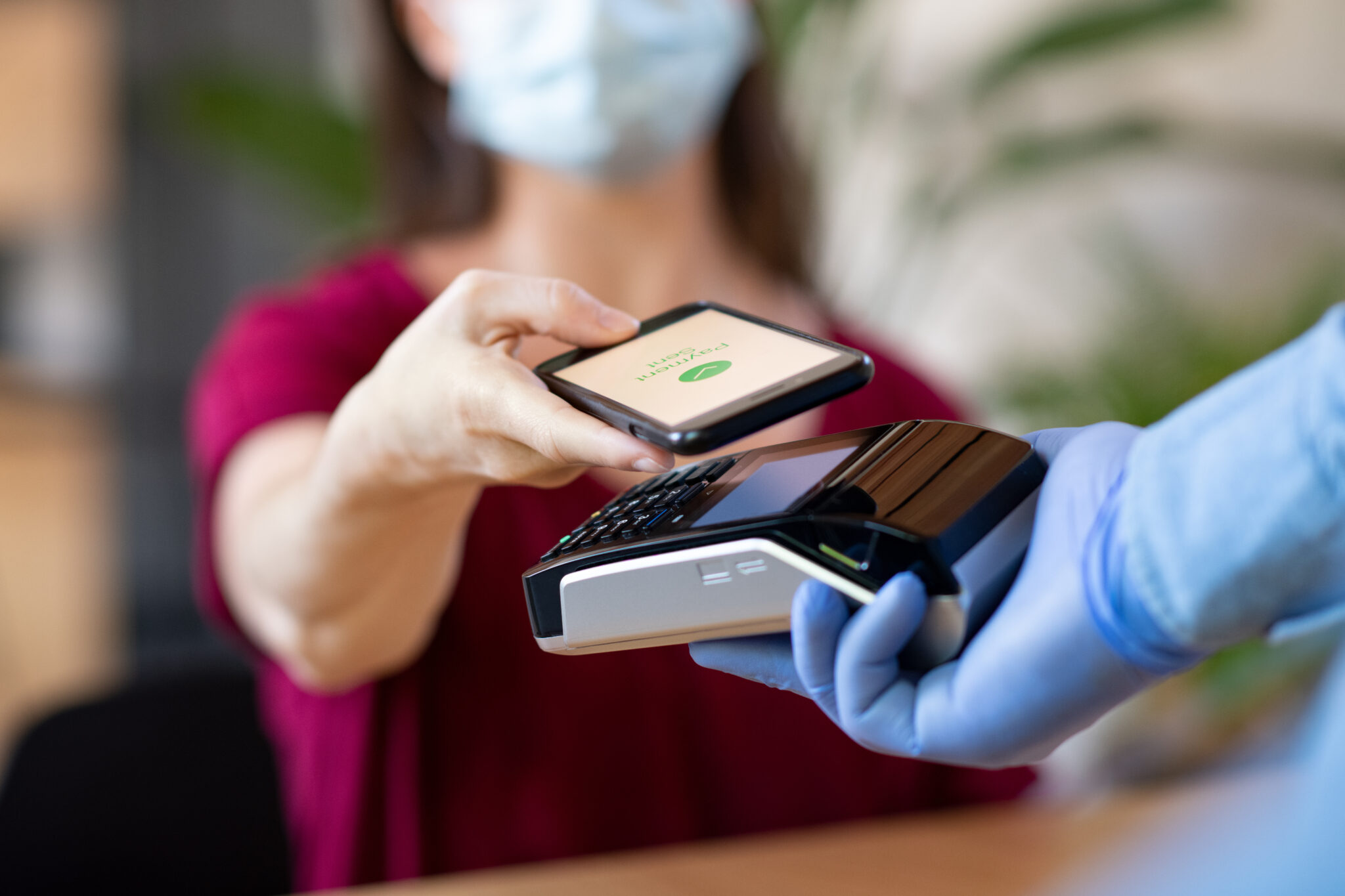 woman holding smartphone over a payment reader