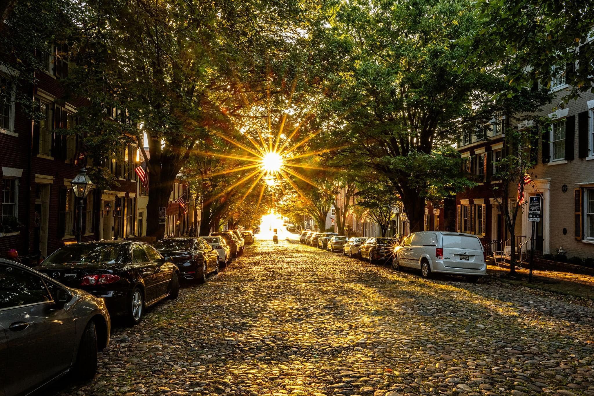 Cobblestone street with the sun rising over it.