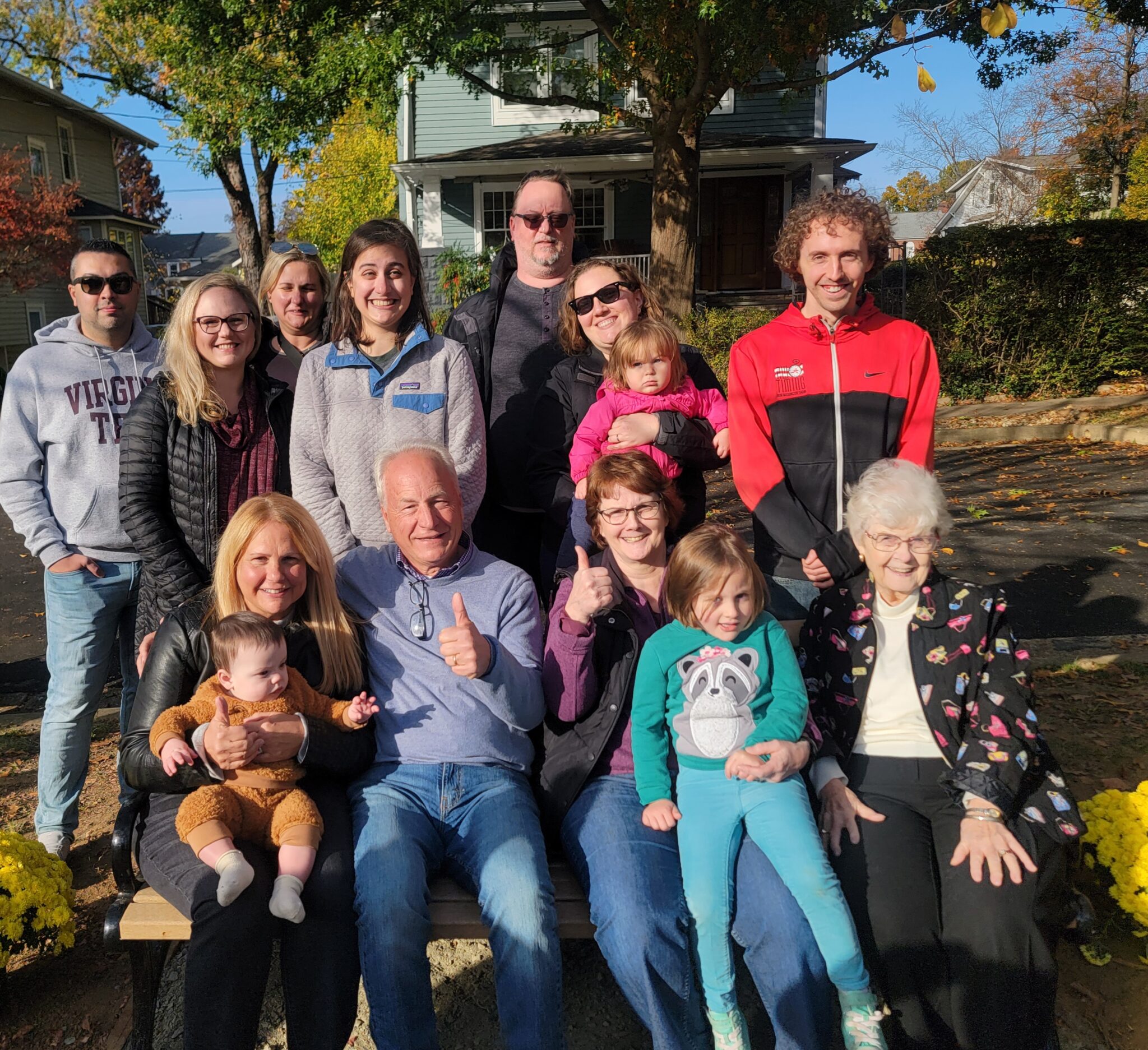 Grop of people assemble on bench in fall and look at camera.