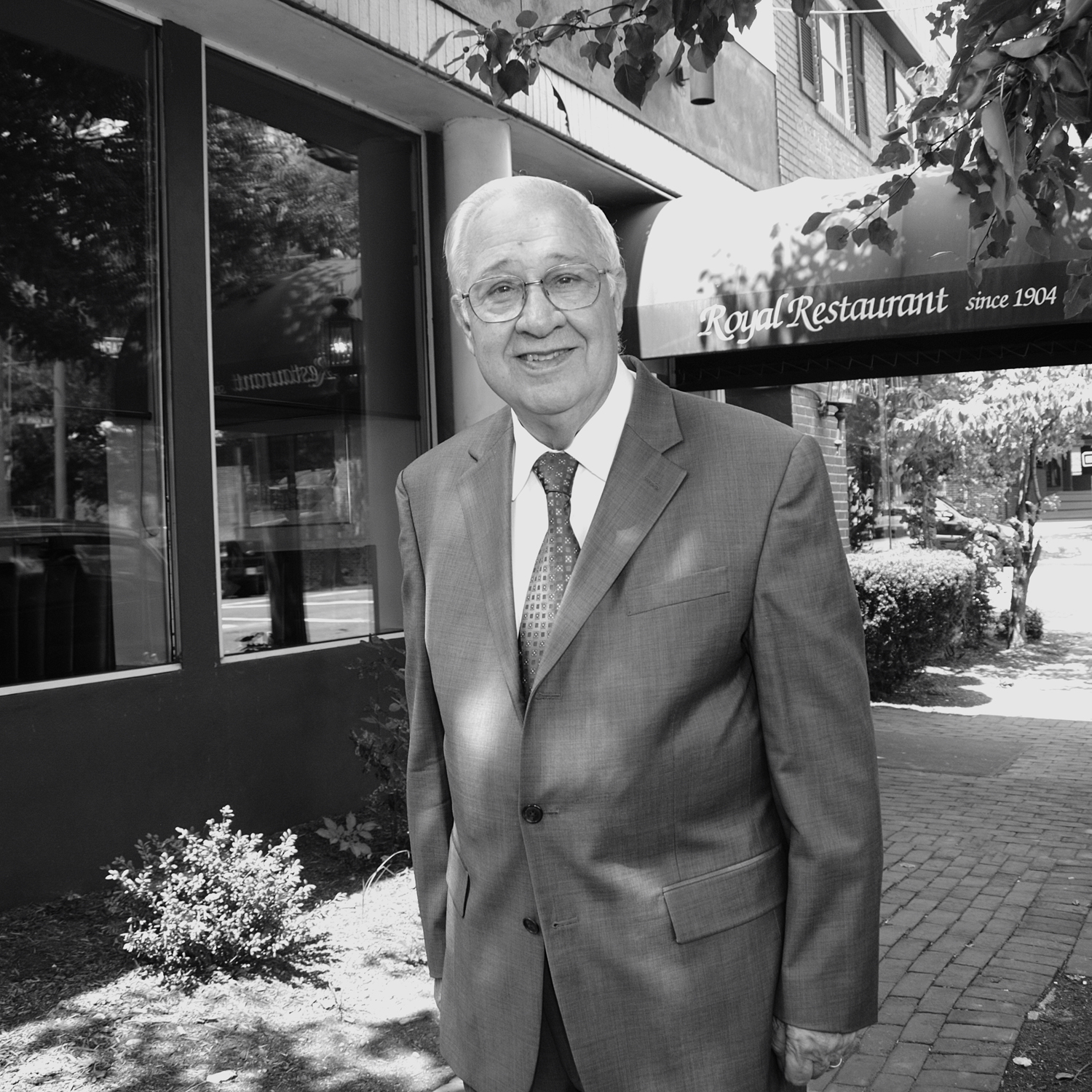 Older man in a suit outside The Royal Restaurant smiling into the cameral.