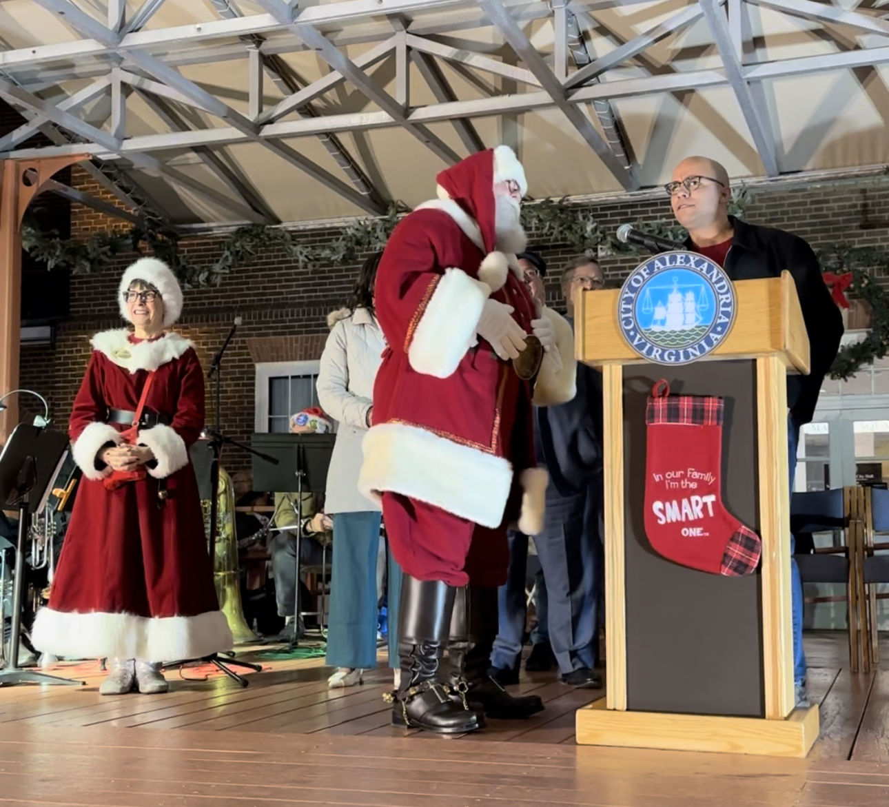 Santa and Mrs. Claus on stage with Mayor of Alexandria shaking his hand.