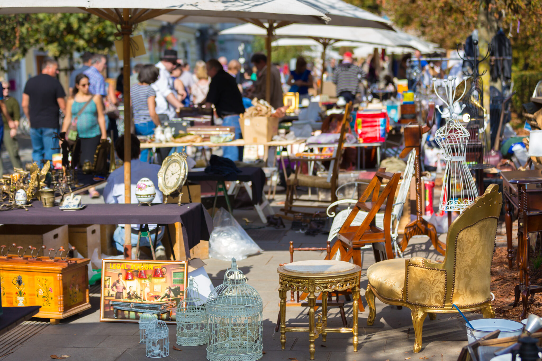 Typical flea market scene with people poring over antiques amongst vendor tents.