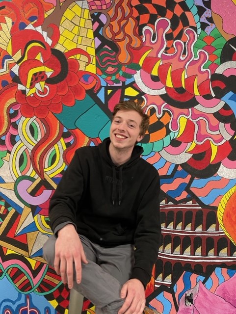 young caucasian man with mural behind him 