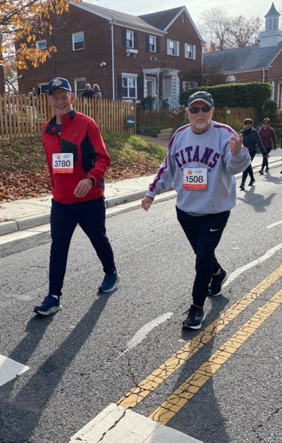 Two men walking with marathon numbers attached to their chests.