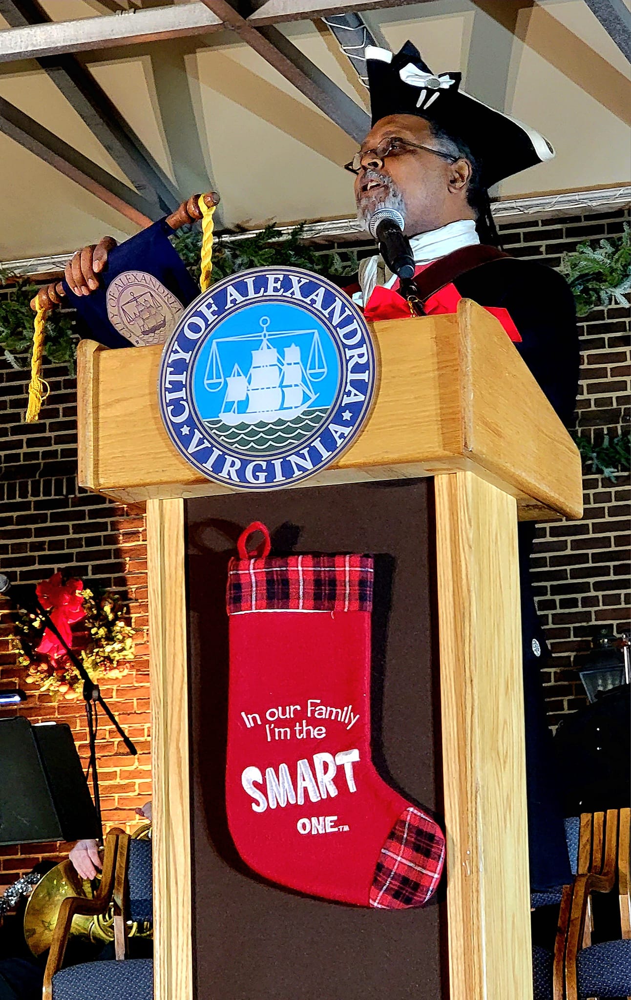 Black man in colonial American dress is at podium reading a scroll.