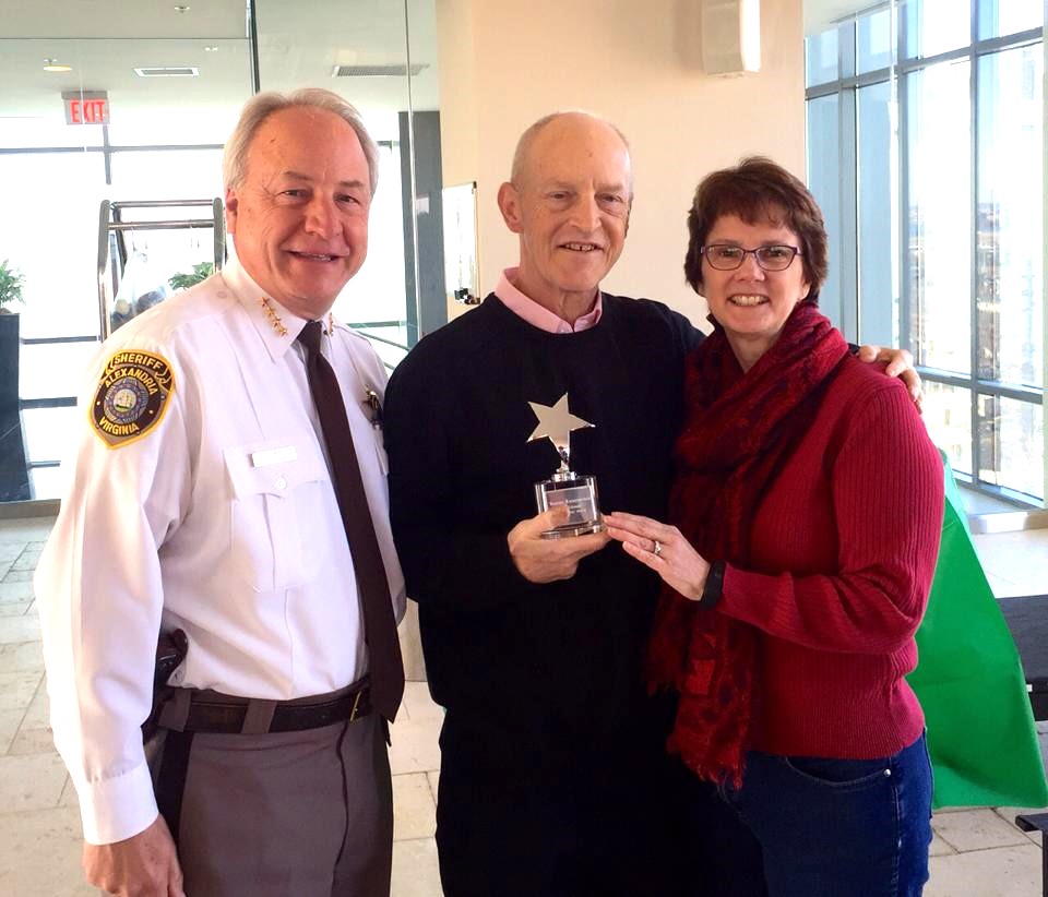 Two men and a woman hold a crystal award with a silver star.