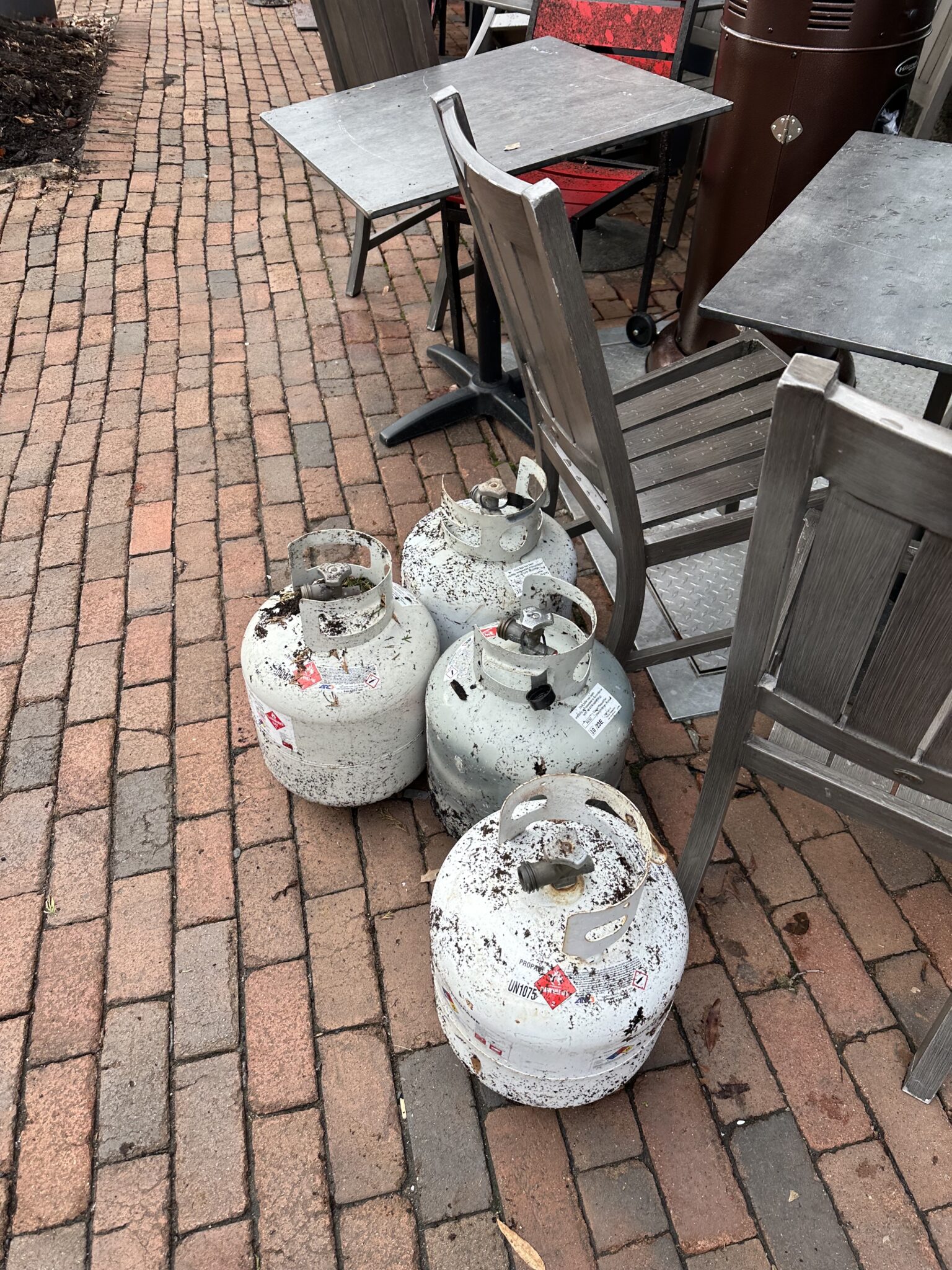 Four muddy propane tanks pushed together on the sidewalk in front of The Majestic Restaurant.