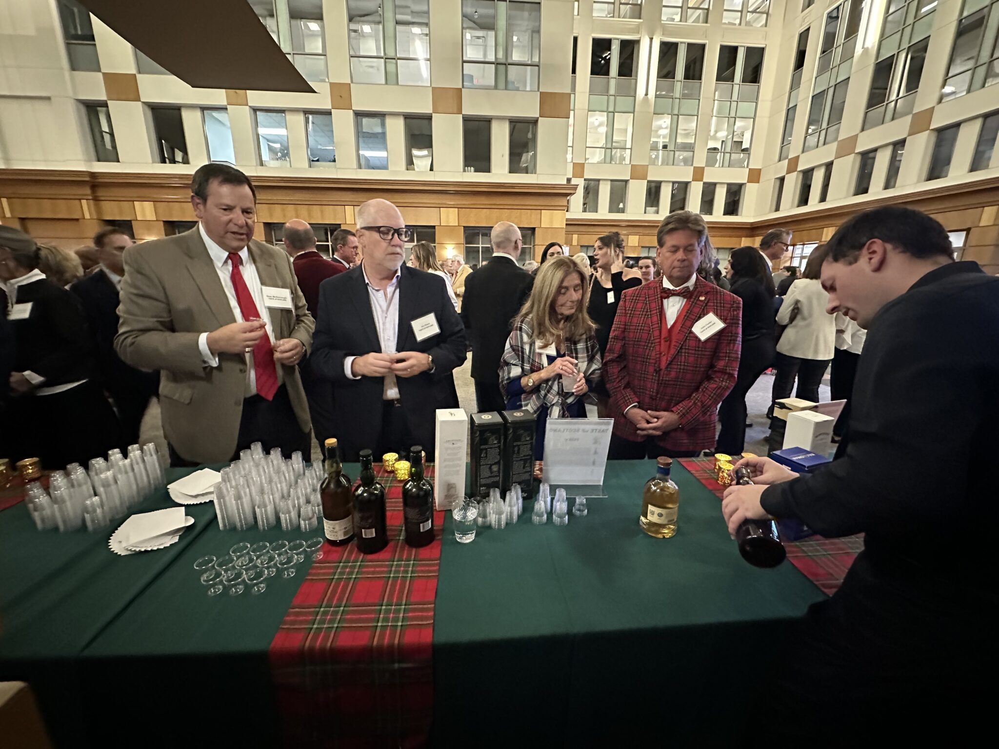 People standing at a tasting table waiting for whiskey samples.