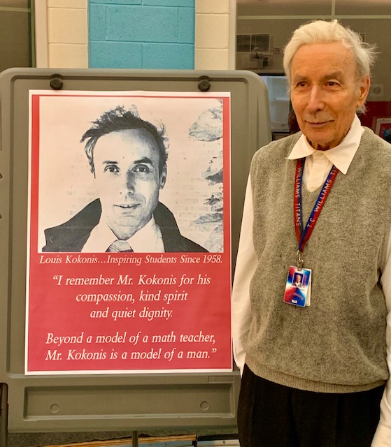 Older man stands next to poster of himself as a younger man 60 years before.