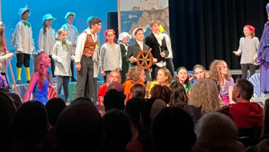 Children on stage in costume with audience looking toward them.