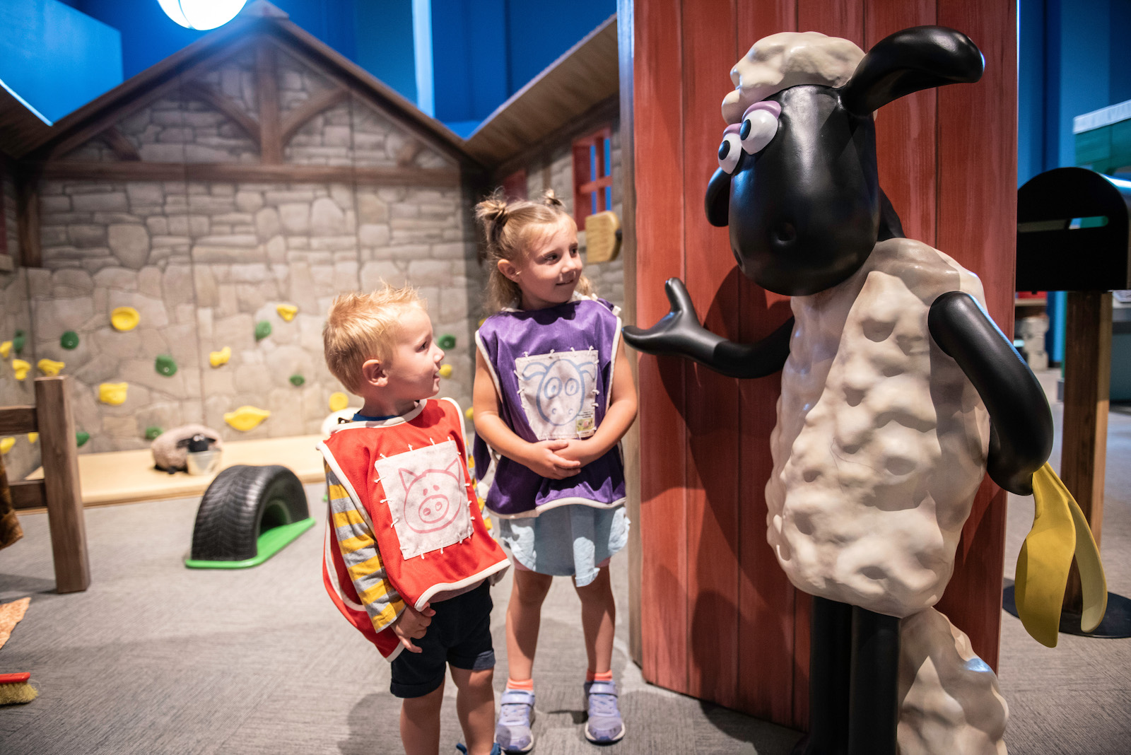 two children interacting with a large sheep character 