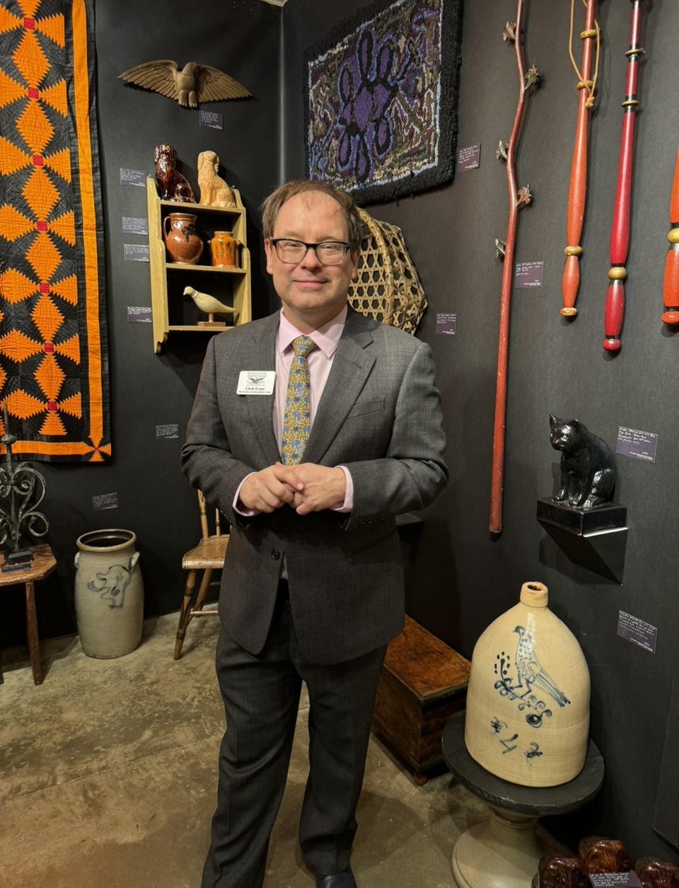 Well dressed man in room filled with art and antiques.