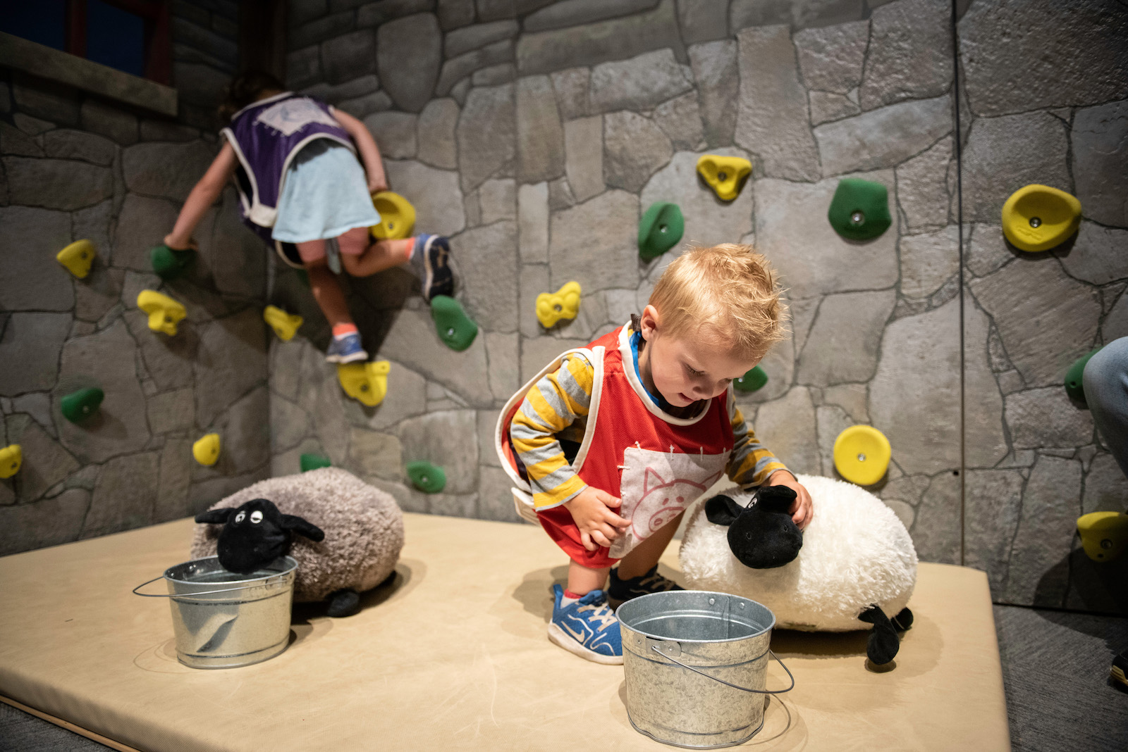 Toddler playing with interactive sheep toy at Children's Museum. 