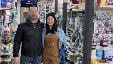 Man and woman smiling and facing camera in hardware store.