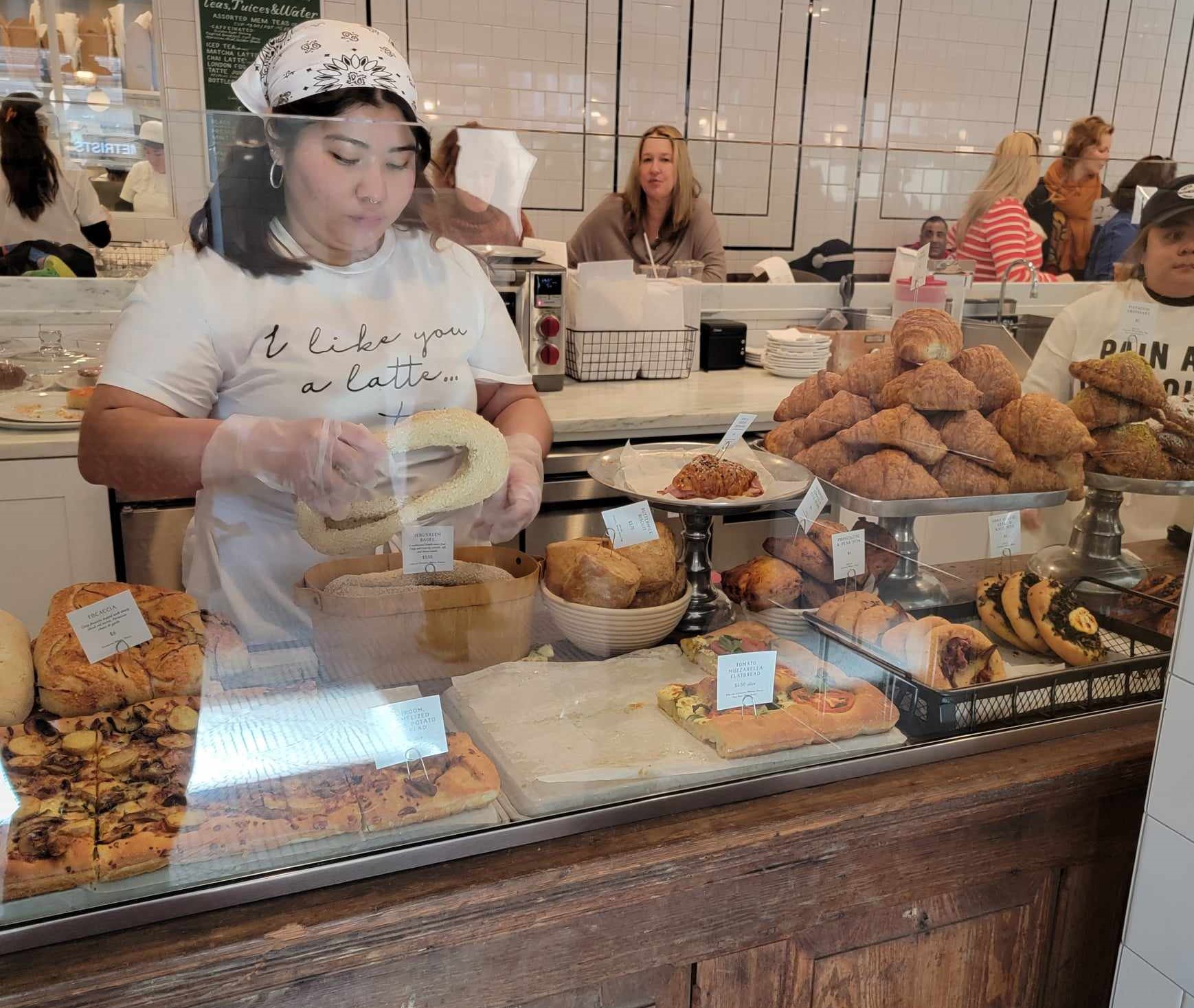 Worker lady adds bread to a bag behind bakery counter