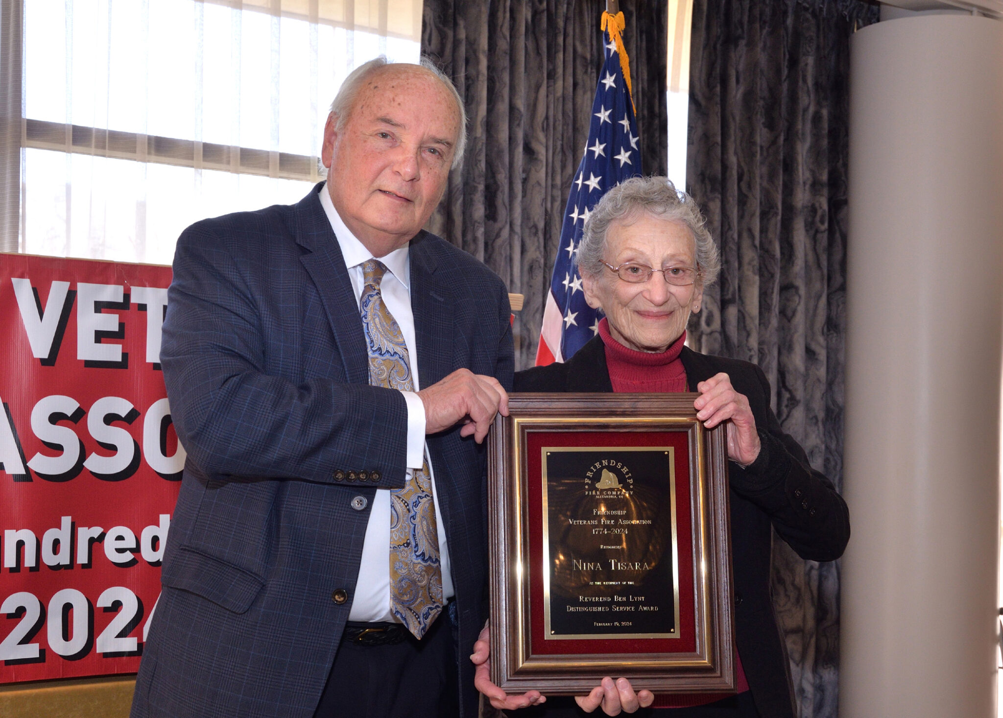 Man and woman standing next to each other holding plaque.