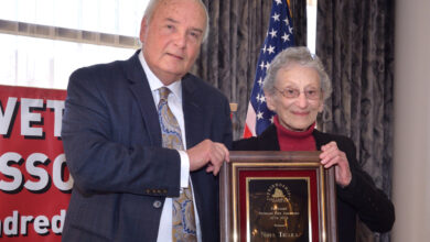 Man and woman standing next to each other holding plaque.