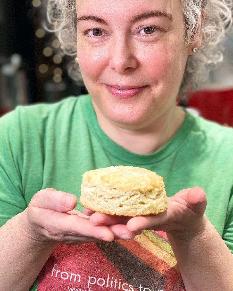 white haired lady holding freshly made biscuit