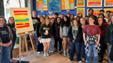 A group of students standing near artwork in the Nepenthe Gallery.