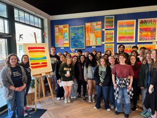 A group of students standing near artwork in the Nepenthe Gallery.