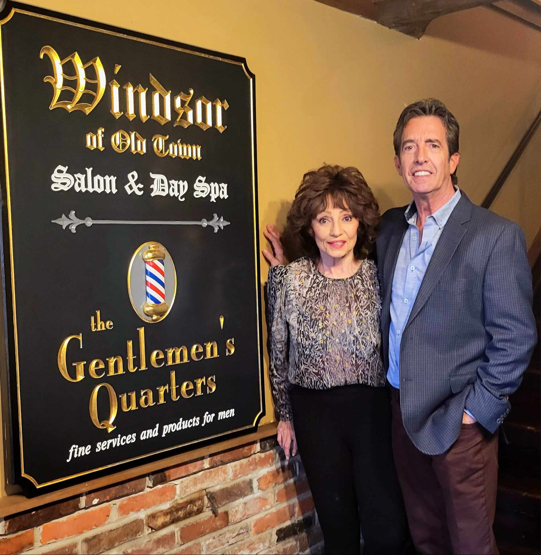 Man and woman stand next to a sign on the wall