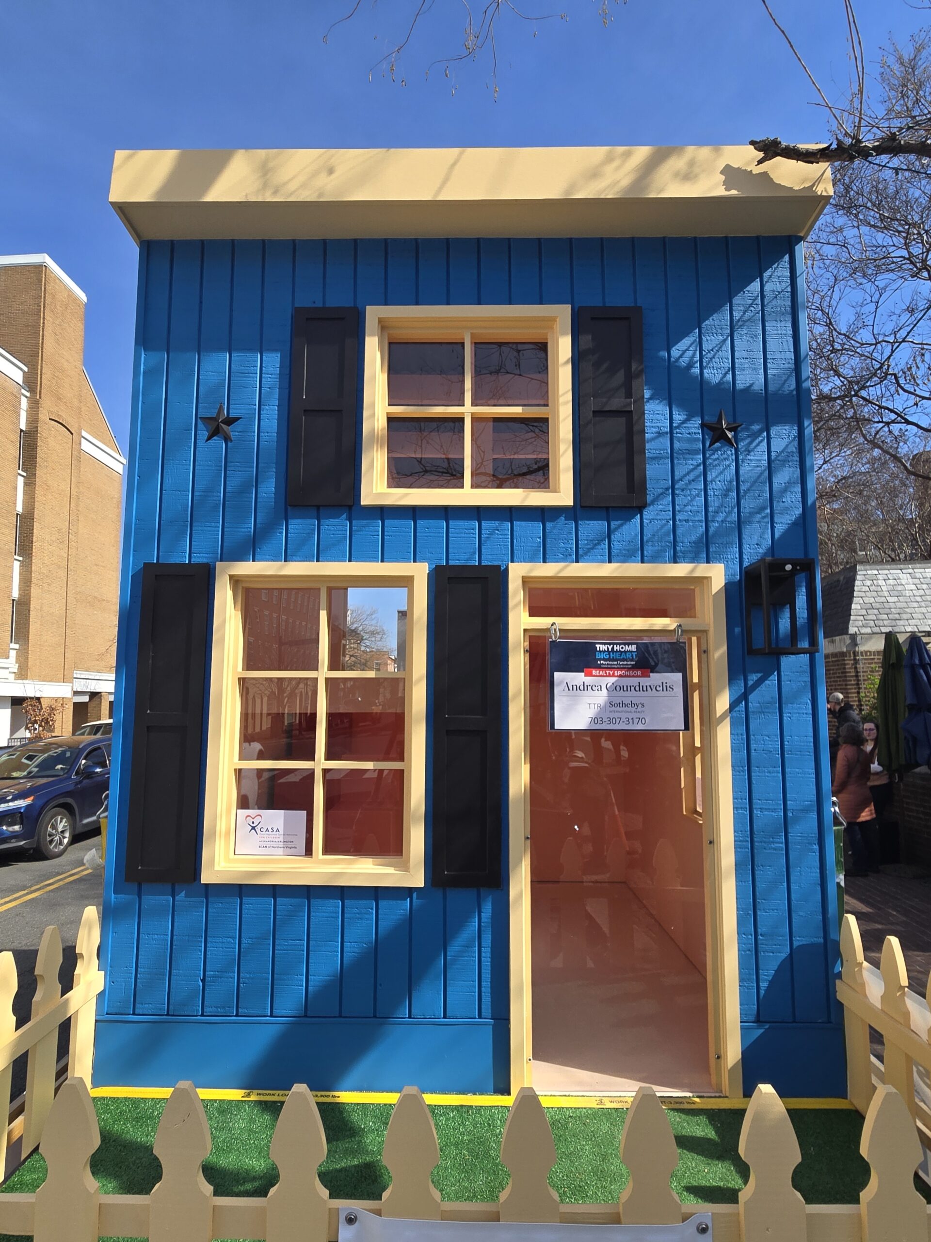 Blue wooden townhouse playhouse with yellow window frames