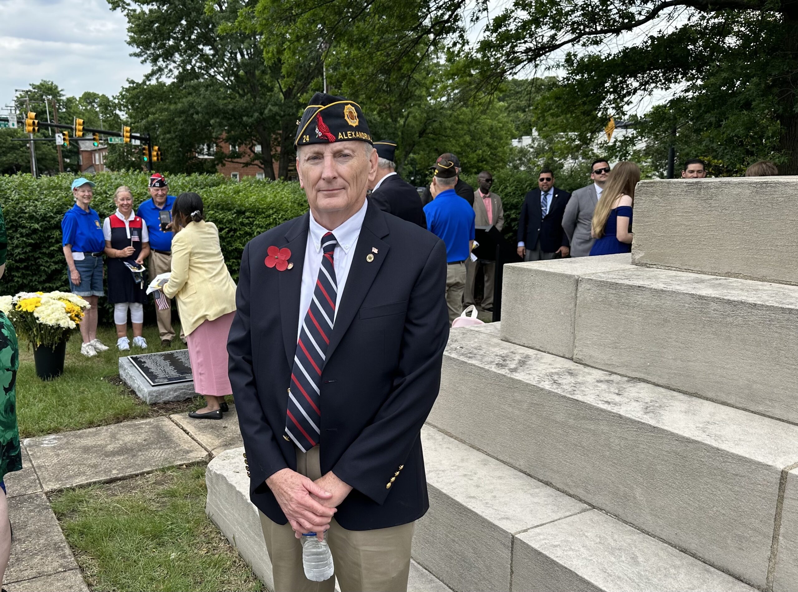 Man in a coat and tie wearing a veteran's hat