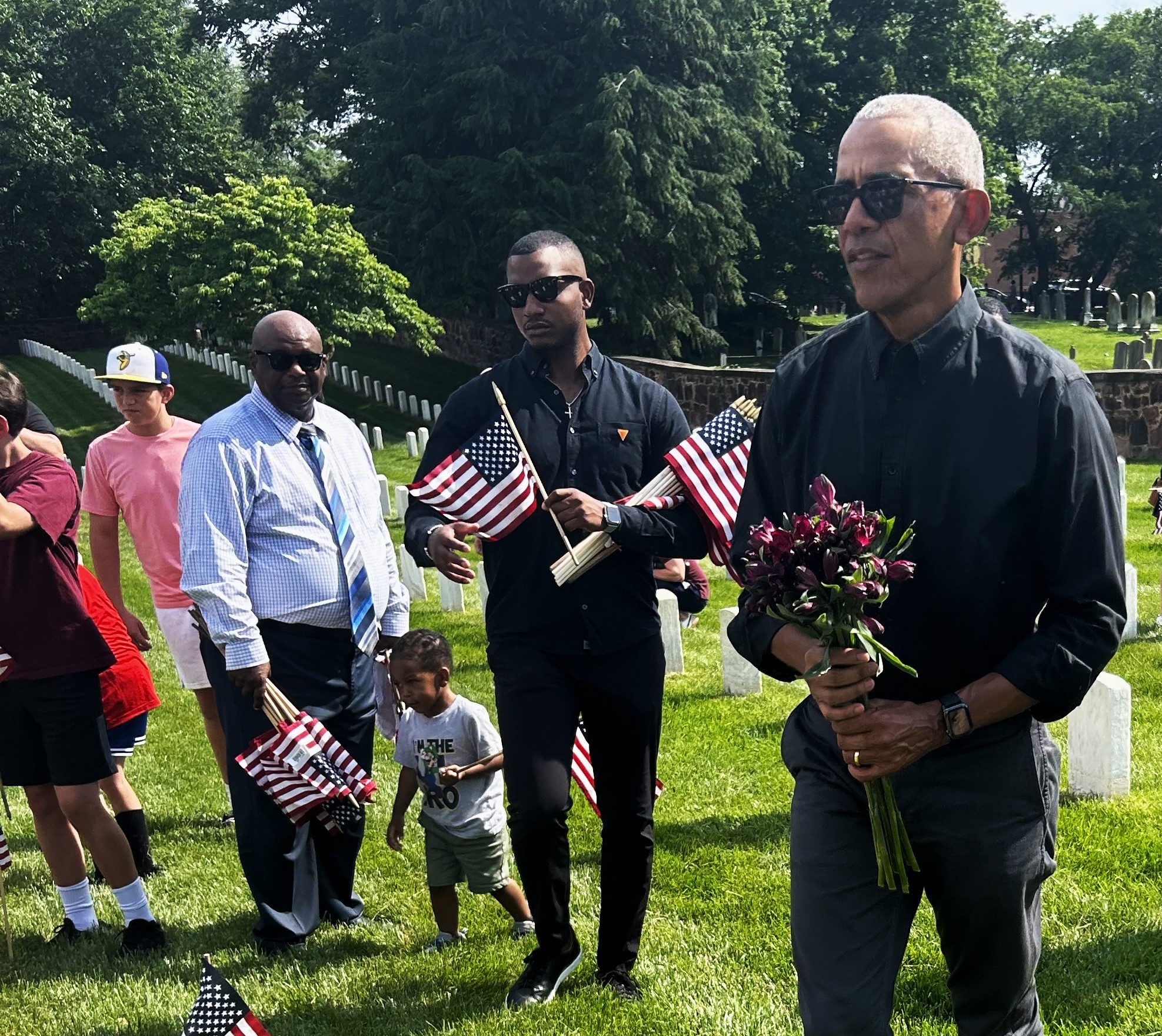 President Barack Obama holding small bouquet of flowers for soldier grave.