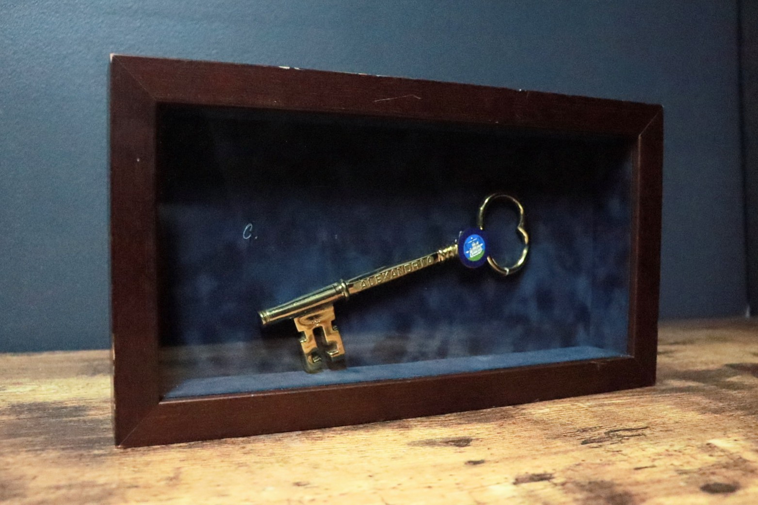 Brass key in a frame behind glass