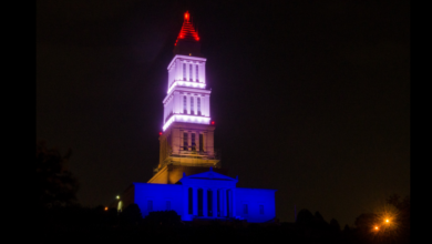 Big building with a spire, at night, in red, white and blue.