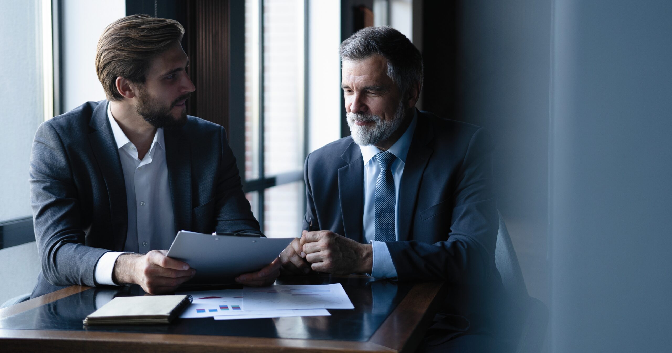 Senior and junior businessman discuss something during their meeting, office background. Senior and junior businessman discuss something during their meeting, office background.