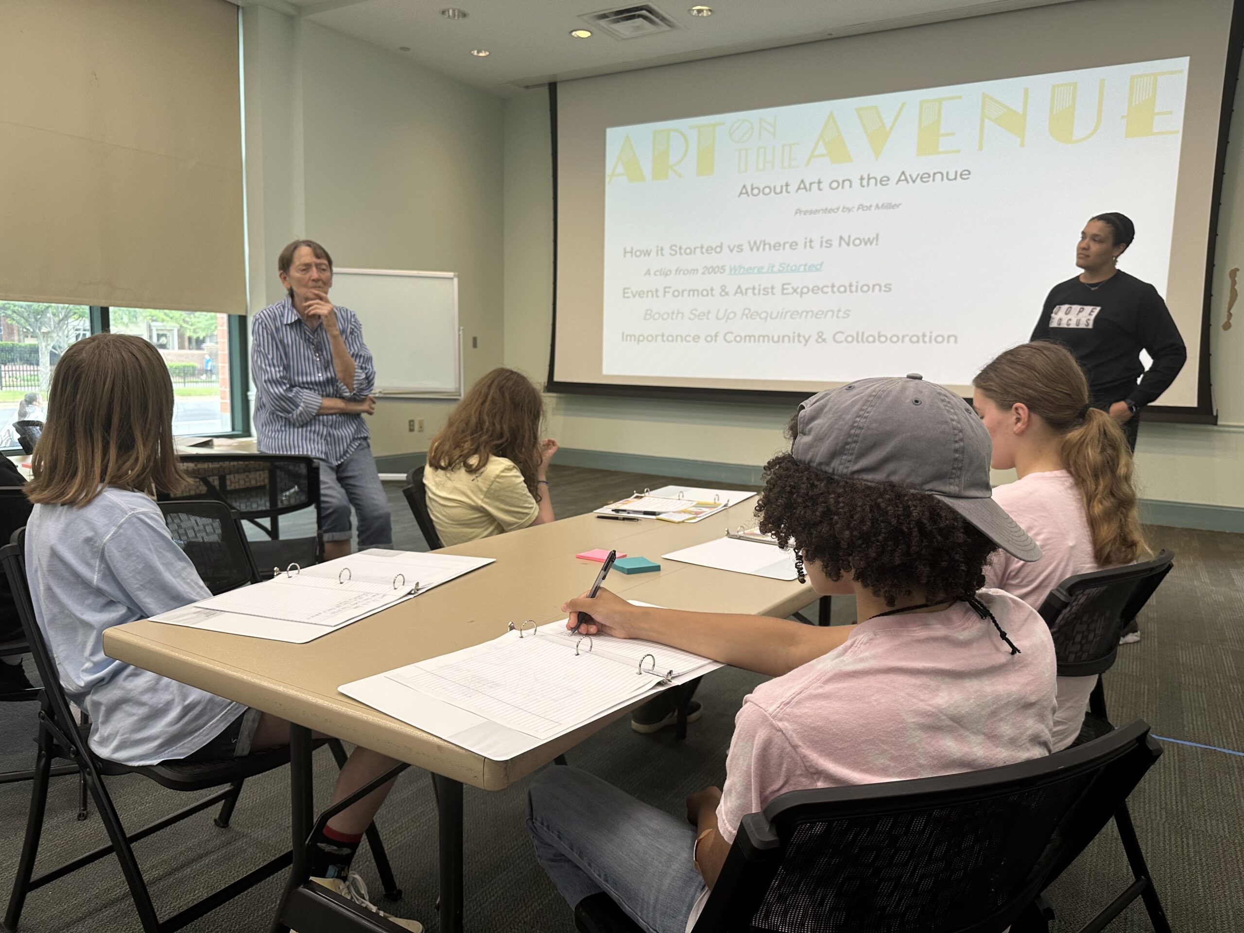 AA1 Pat Miller and Amber Bryson discuss the history of Art on the Avenue with Avenue Ambition participants. PHOTO BY EL SIMMONS