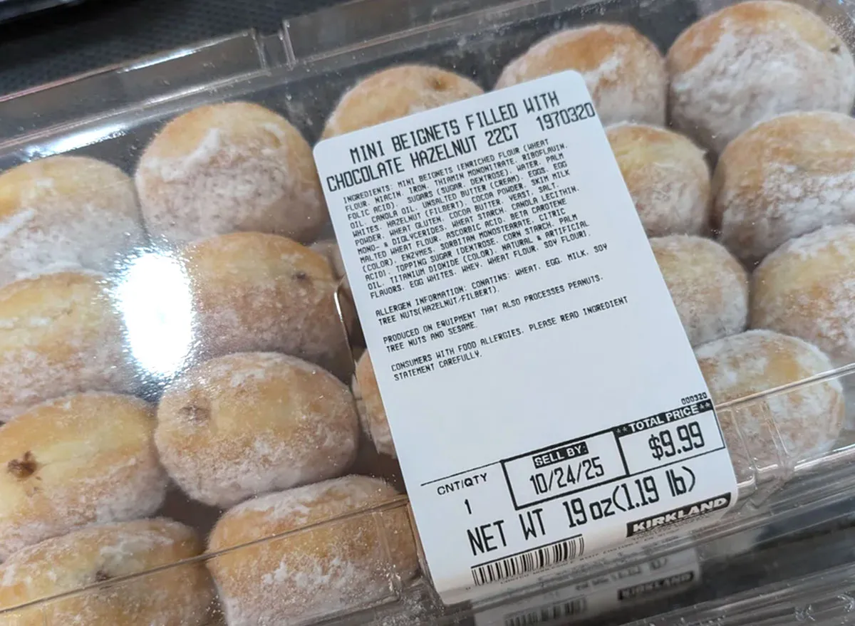 Plastic bakery container of powdered sugar–coated mini beignets filled with chocolate hazelnut, labeled Kirkland Signature, priced at $9.99.
