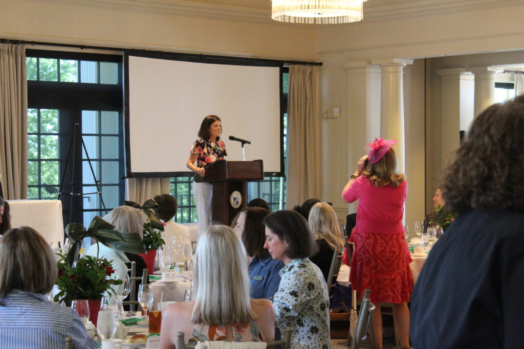 Lorri Ring speaks in front of microphone at annual Twig luncheon.