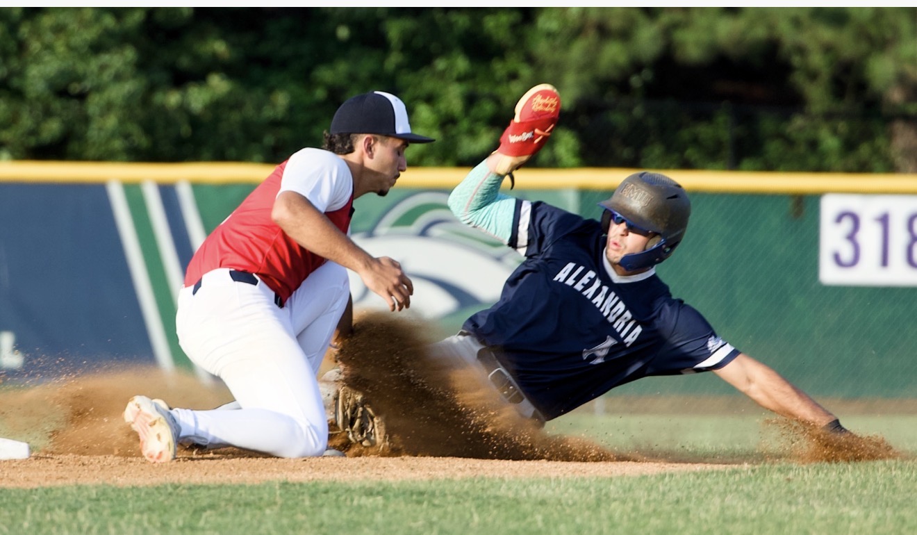 Daniel McGinnis Slides Home Safely Alexandria Aces runner Daniel McGinnis slides through a cloud of dust as a South County Braves infielder attempts a tag during a Cal Ripken League game at Frank Mann Field.