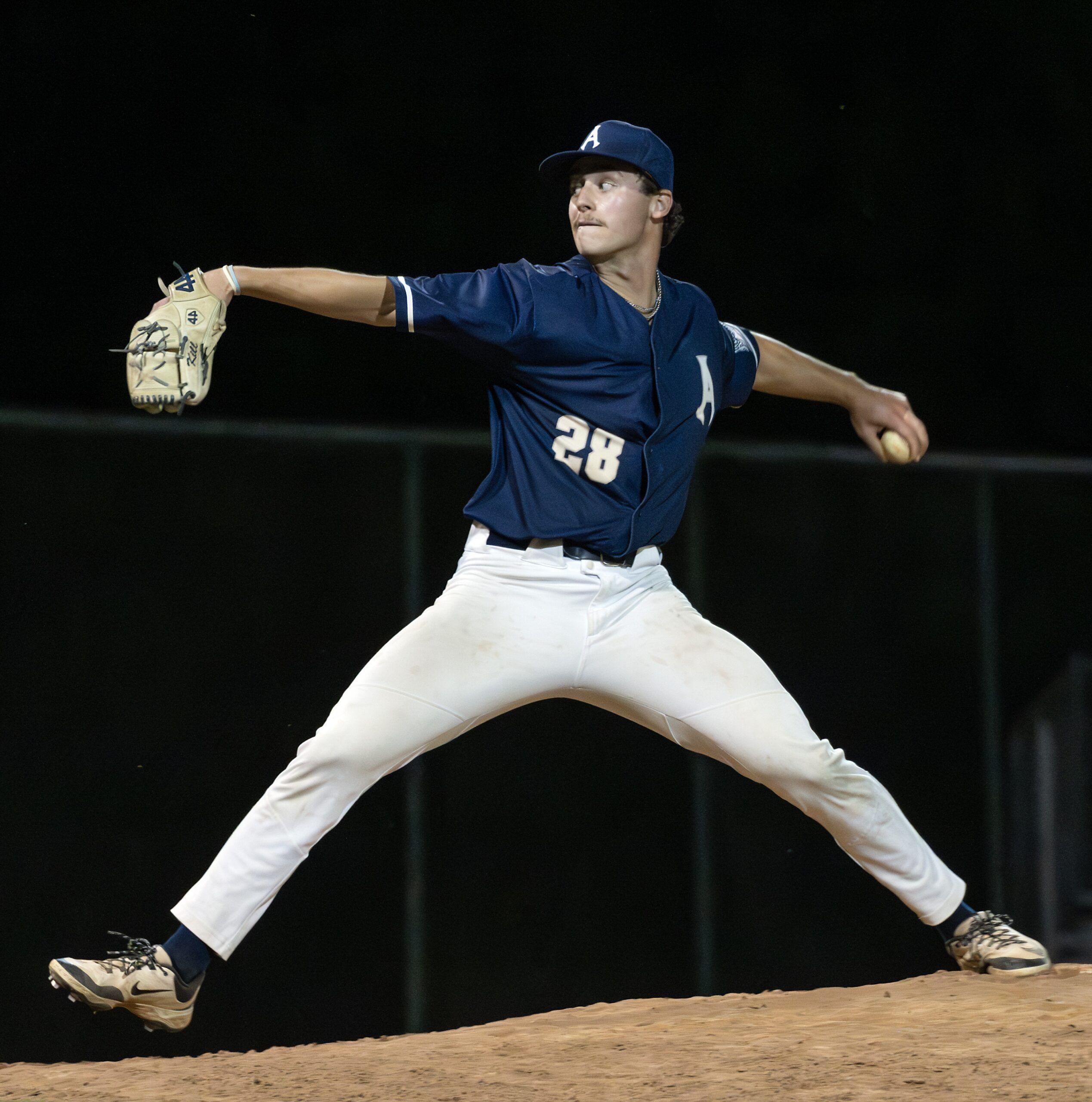 ACES Jack Warner 1 Alexandria Aces pitcher Jack Warner delivers a pitch from the mound during a nighttime baseball game, his arms extended and front leg stretched wide in mid-throw.