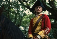 Actor William Franklyn-Miller portrays a young George Washington in British colonial military uniform while seated on horseback in a wooded setting in a scene from the feature film Young Washington.