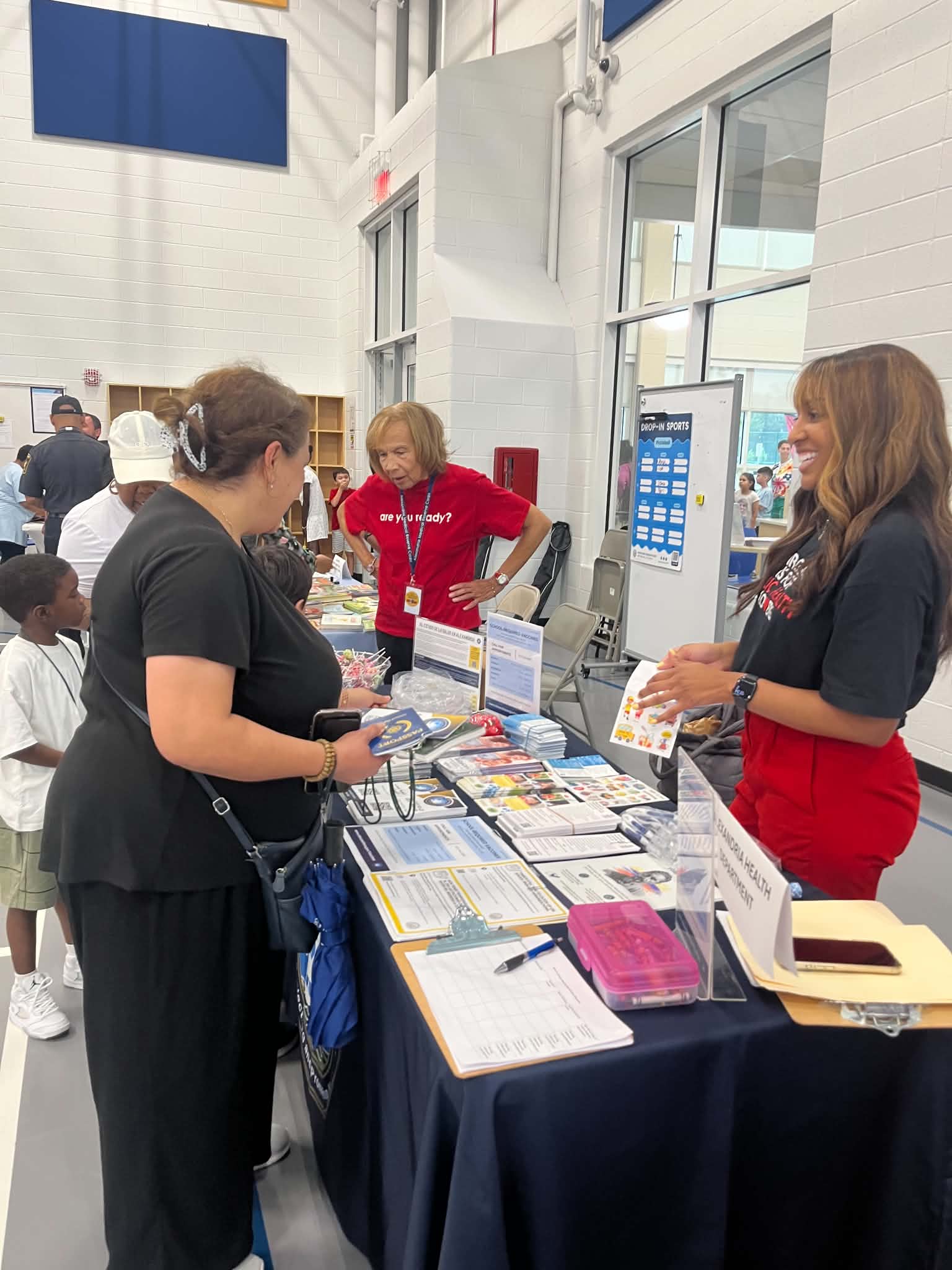 An Alexandria Health Department representative speaks with a parent at an information table during METWC’s Back 2 School Slam Jam at Patrick Henry Recreation Center.