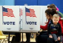 A voter casts a ballot while holding a young child inside a polling place during Virginia's primary election.