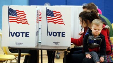 A voter casts a ballot while holding a young child inside a polling place during Virginia's primary election.