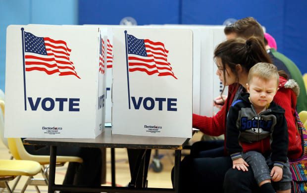 Voters Cast Ballots During Virginia Primary Election A voter casts a ballot while holding a young child inside a polling place during Virginia's primary election.