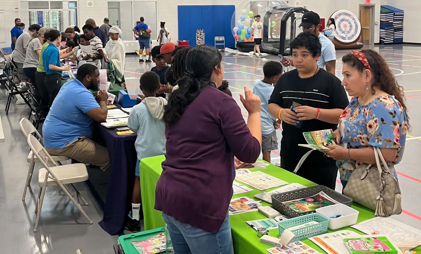 Families and children speak with representatives at community resource tables inside Patrick Henry Recreation Center during METWC’s Back 2 School Slam Jam.