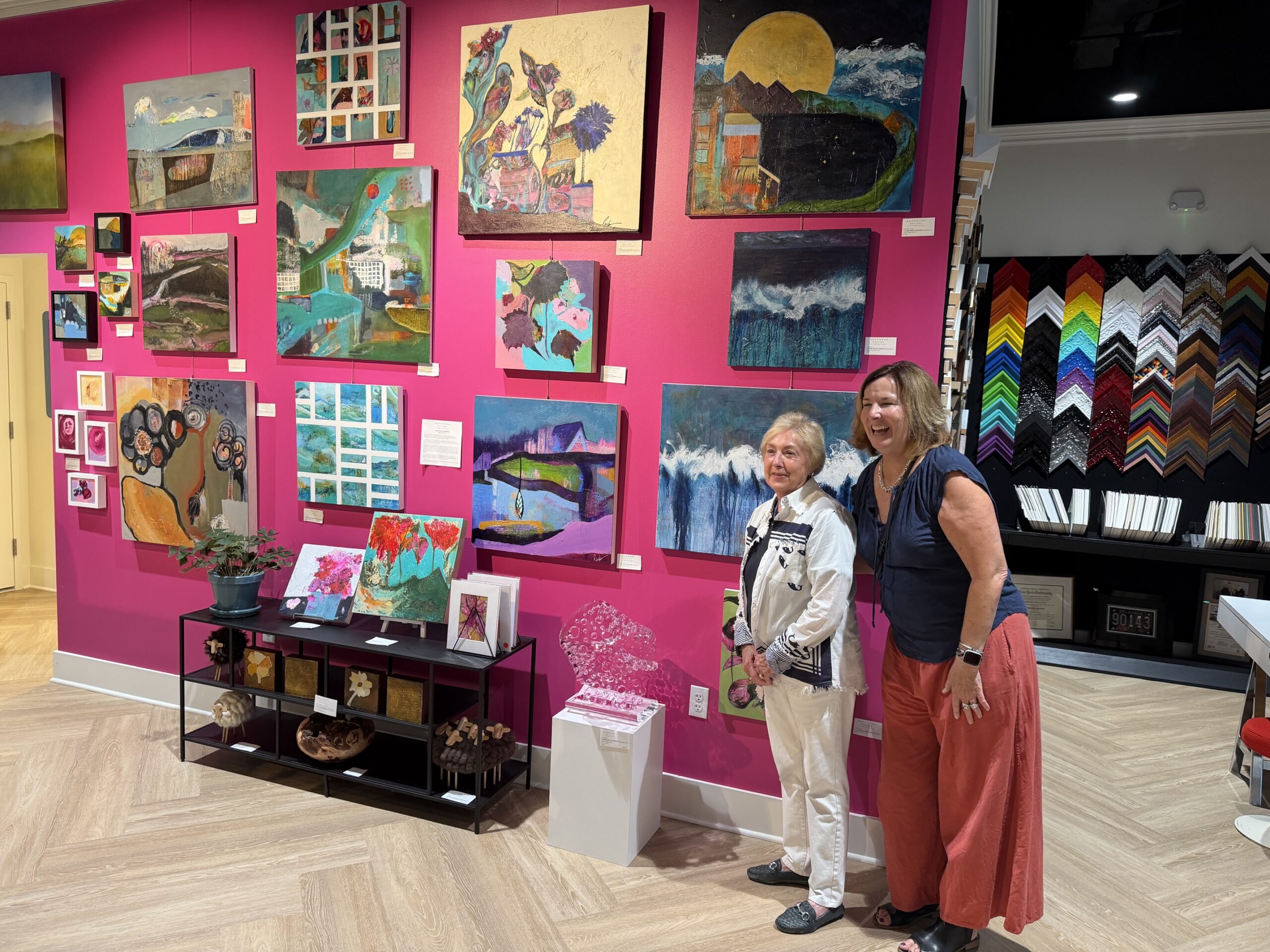 Lori Welch Brown at Nepenthe Gallery Alexandria artist and Nepenthe Gallery staff member Lori Welch Brown stands with a guest in front of a wall of colorful artwork.