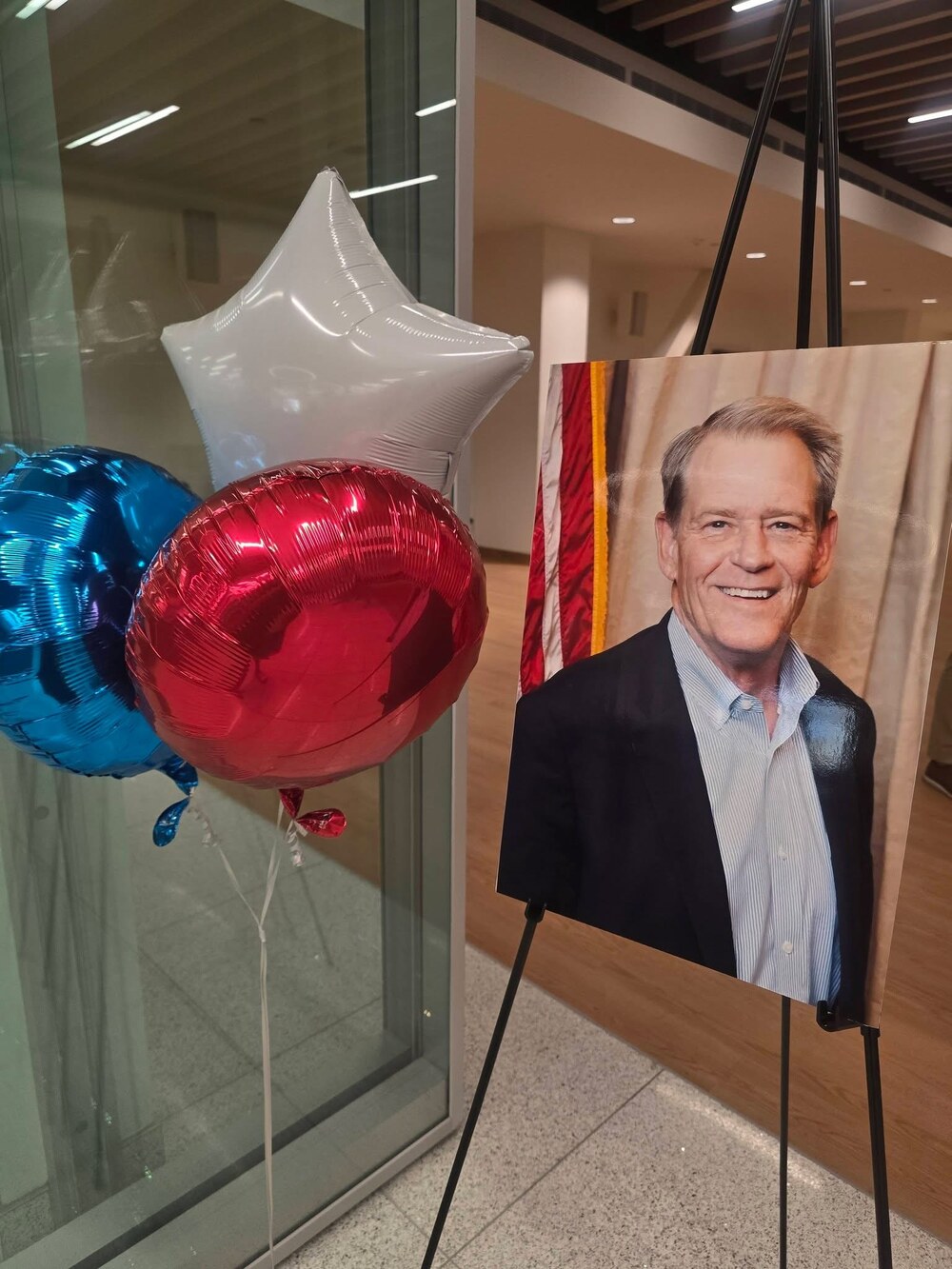 A portrait of former Alexandria Mayor Kerry J. Donley displayed with red, white and blue balloons at the athletic field dedication.